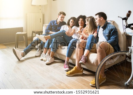 Group of friends sitting on the sofa at home take a selfie with the smart phone - Millennials have fun together in an apartment