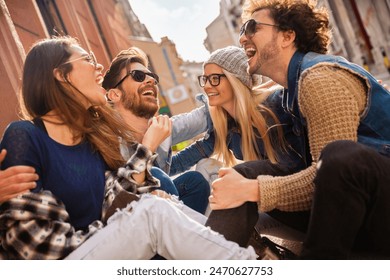 Group of friends sitting on street laughing and talking - Powered by Shutterstock