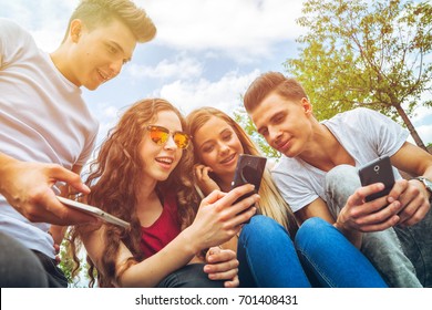 Group of friends sitting together using their mobile phones - Powered by Shutterstock