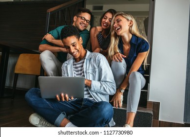 Group Of Friends Sitting And Watching Something On A Laptop Computer