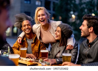 Gruppe von Freunden, die in der Brauerei lächeln und trinken, Treffen von einigen Jahrtausenden toastenden mit Bier und essen Fusionsnahrung, Nachtleben und soziale Zusammenkunft von jungen Menschen nach dem Ausbruch des Covid19