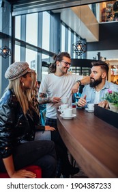 Group Of Friends Are Socializing And Drinking Coffee While Sitting Together At Cafe