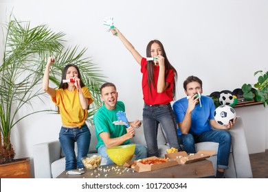 Group of friends sport fans watching match in colorful shirts holding horns and hand clappers - Powered by Shutterstock