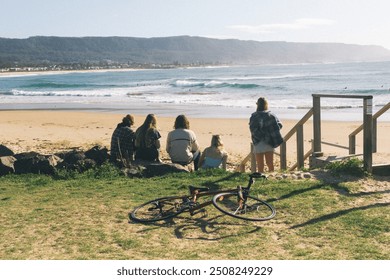 A group of friends stands on the beach, backs to the camera, gazing at the surf. Their silhouettes are framed by the rolling waves and golden light, capturing a moment of shared anticipation and joy. - Powered by Shutterstock