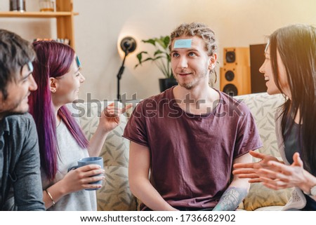 Group of friends with sticky notes on foreheads playing name game at home