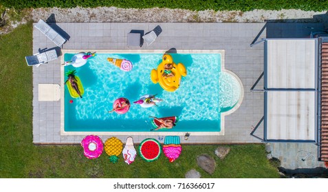 Group Of Friends Sunbathing On Cool Air Matress In A Swimming Pool, View From Above - Pool Party, People Relaxing And Enjoying Summer