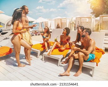 Gruppe von Freunden mit Badeanzug trinken einen Cocktail am Strand
