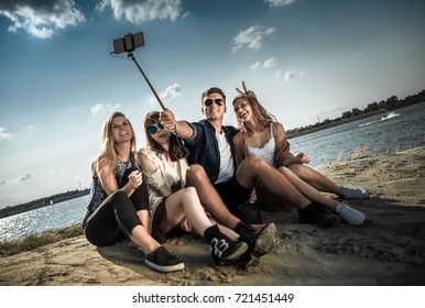 Group Of Friends Taking Self Portrait With Selfie Stick, Having Fun At The Beach