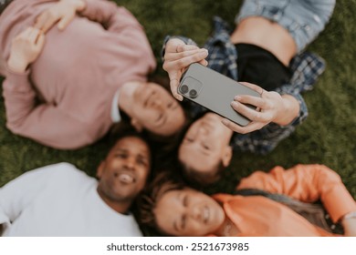 Group of friends taking a selfie blurry image. Diverse friends lying on grass, smiling. Diverse group of friends enjoying time together. Friends capturing memories with a selfie. Blurry photography. - Powered by Shutterstock