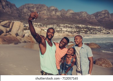 Group of friends taking selfie on beach. Best friends standing along rocky coastline and taking a self portrait with smart phone. - Powered by Shutterstock