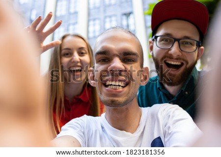 Group of friends taking a stroll on city's street in summer day. Handicapped man with his friends having fun. Inclusion and diversity concept, normal lifestyle of special groups of society.