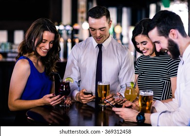 Group of friends texting and having a drink in a bar