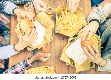 Group of friends toasting beer glasses and eating at fast food - Happy people partying and eating in home garden - Young active adults in a picnic area with burgers and drinks