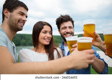 Group of friends toasting with beer in plastic glasses