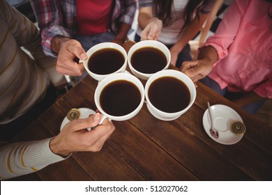 Group Of Friends Toasting Cup Of Coffee In Cafe