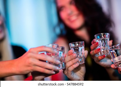Group of friends toasting tequila shot glasses in bar - Powered by Shutterstock