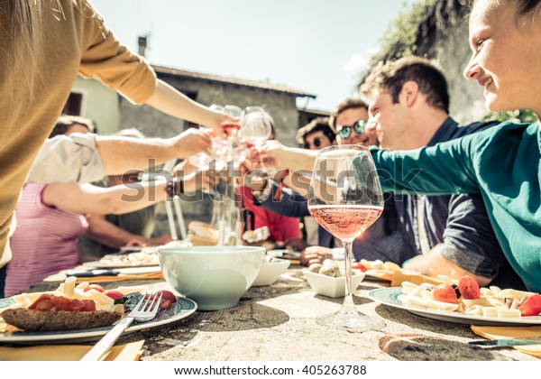 Group of friends toasting\
wine glasses and having fun outdoors - People having lunch in a\
restaurant