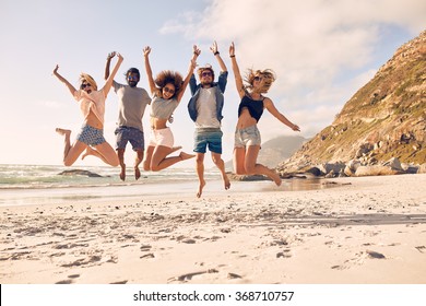 Group Of Friends Together On The Beach Having Fun. Happy Young People Jumping On The Beach. Group Of Friends Enjoying Summer Vacation On A Beach.