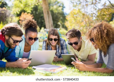 Group Of Friends Using Laptop, Mobile Phone And Digital Tablet In Park