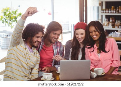 Group of friends using laptop while having cup of coffee in cafe