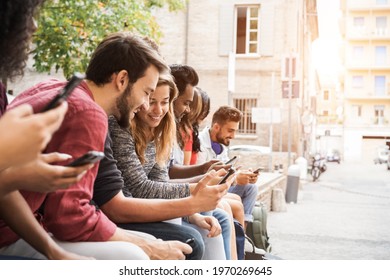 Group of friends using mobile phones outdoors in city park - Soft focus on blond girl face