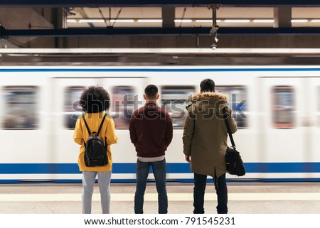 Group of friends waiting the train in the platform of subway station. Public transport concept.