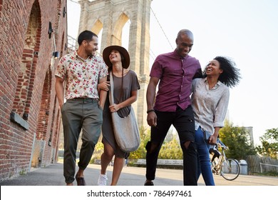 Group Of Friends Walking By Brooklyn Bridge In New York City