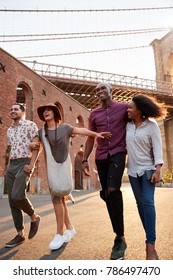 Group Of Friends Walking By Brooklyn Bridge In New York City