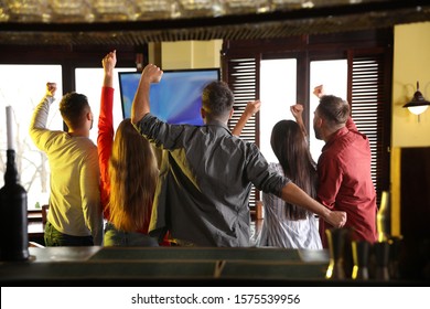 Group Of Friends Watching Football In Sport Bar, Back View