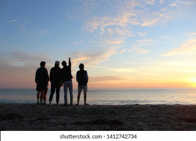 Group Of Friends Watching The Sunrise On The Beach