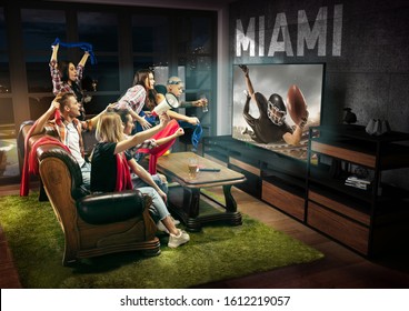 Group Of Friends Watching TV, American Football Match, Championship. Emotional Men And Women Cheering For Favourite Team, Look On Fighting For Ball. Concept Of Friendship, Sport, Competition, Emotions