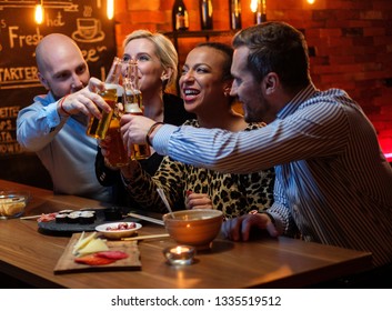 Group Of Friends Watching Tv In A Cafe Behind Bar Counter