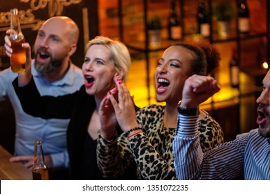 Group Of Friends Watching Tv In A Cafe Behind Bar Counter