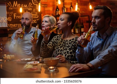 Group Of Friends Watching Tv In A Cafe Behind Bar Counter