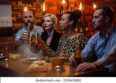 Group Of Friends Watching Tv In A Cafe Behind Bar Counter