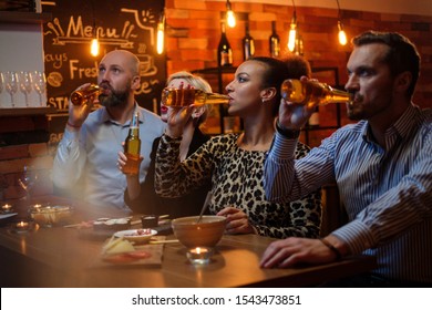 Group Of Friends Watching Tv In A Cafe Behind Bar Counter