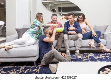 Group Of Friends Watching Tv And Eating Popcorn On Sofa