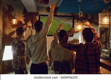 A group of friends watching tv football in a sports bar.
