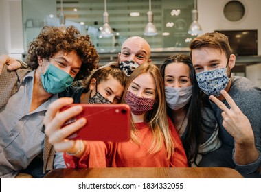 Group of friends wearing protection mask at the restaurant - Young happy people celebrating taking a selfie with smartphone - People, technology and new normal lifestyle concept. - Powered by Shutterstock