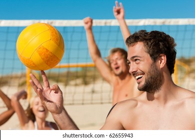 Group of friends - women and men - playing beach volleyball, one in front doing tricks to the ball