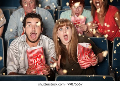 Group of frightened people watching movie spill popcorn - Powered by Shutterstock
