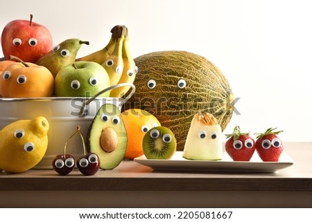 Group of fruits with eyes in containers on wooden bench and white isolated background. Fruits and vegetables child healthy eating concept.