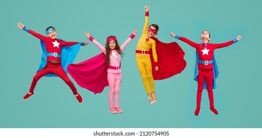 Group of full body boys and girl in colorful superhero costumes clenching fists and pretending to fly while playing isolated on turquoise background - Powered by Shutterstock