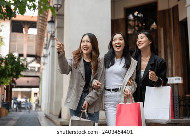 A group of fun, attractive young Asian girl friends are enjoying shopping in the city during their abroad trip together. Leisure, lifestyle, fashion, city life - Powered by Shutterstock