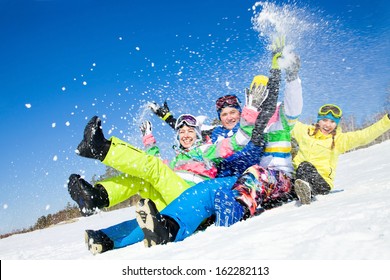 Group Of Funny Friends Slide Downhill Together On Mountain Holiday