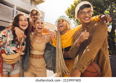 Group of generation z friends laughing together outdoors. Cheerful young friends embracing each other in the summer sun. Youngsters having fun and enjoying their youth. - Shutterstock ID 2119997405