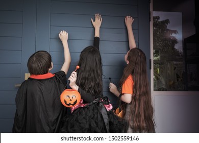 Group Of Girl And Boy Kids Smiling And Dress Up As Halloween Vampire Costume And Knock On Door For Trick Or Treat For Halloween Night Day Theme Coming Soon Together, Back View