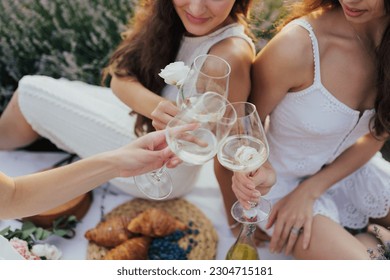 A group of girlfriends raise a toast with glasses of white wine. Close shot.	 - Powered by Shutterstock