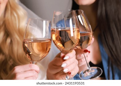 A group of girlfriends raise a toast with glasses of white colored wine. Close shot. - Powered by Shutterstock