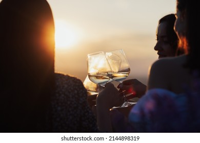 A group of girlfriends toasting glasses with wine at sunset. Together clinking glasses, close-up. - Powered by Shutterstock